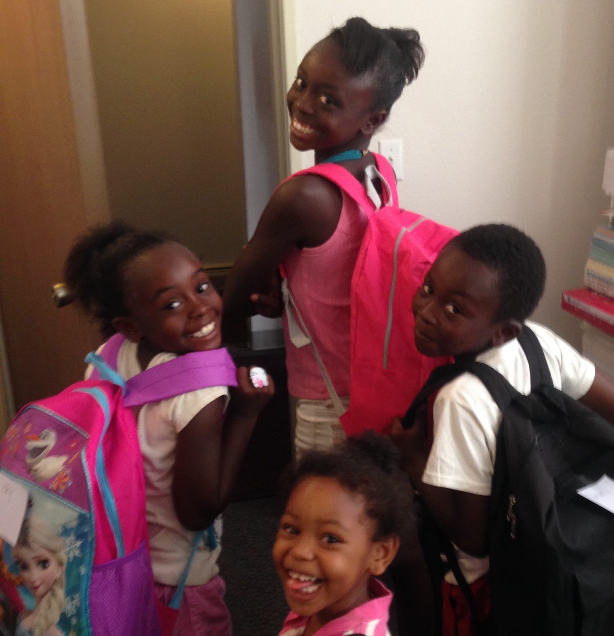 Four smiling children wearing new school backpacks