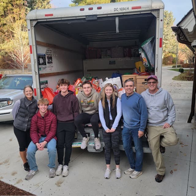 Seven volunteers in front of a moving truck loaded with Adopt A Family gifts